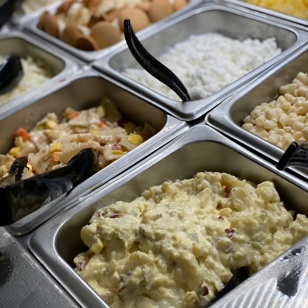 Buffet bar with various American side dishes including potato salad, pasta salad, and cottage cheese.