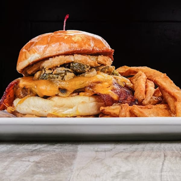 A Sixty Six Grill & Tap House burger with cheese, bacon, and mushrooms, served with fries.