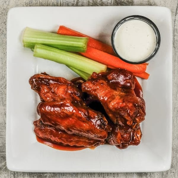 A plate of Sixty Six Grill & Tap House's American-style chicken wings with celery, carrots, and ranch.