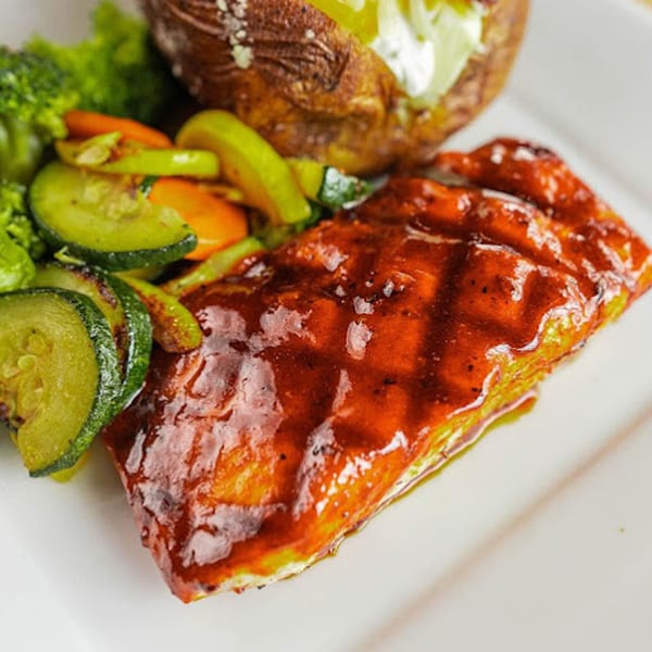 Grilled salmon with BBQ sauce, roasted zucchini, carrots, broccoli, and a baked potato with sour cream.